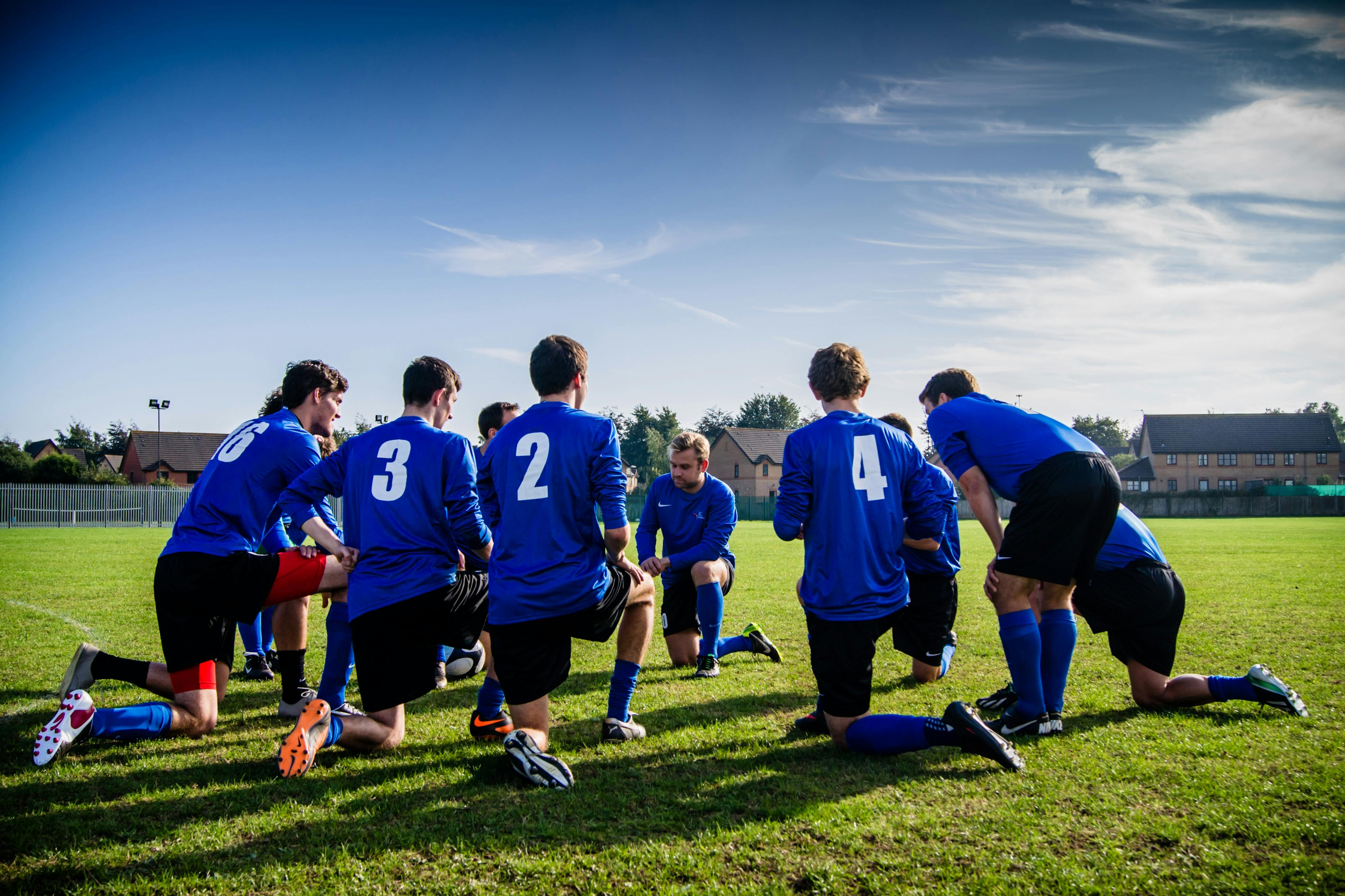 A sports team in a circle kneeling.